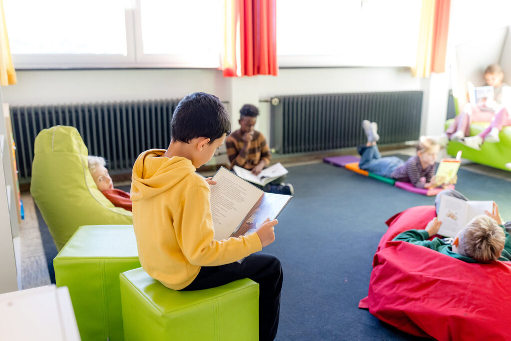 Kinder sitzen zusammen im Klassenraum und beschäftigen sich mit Büchern