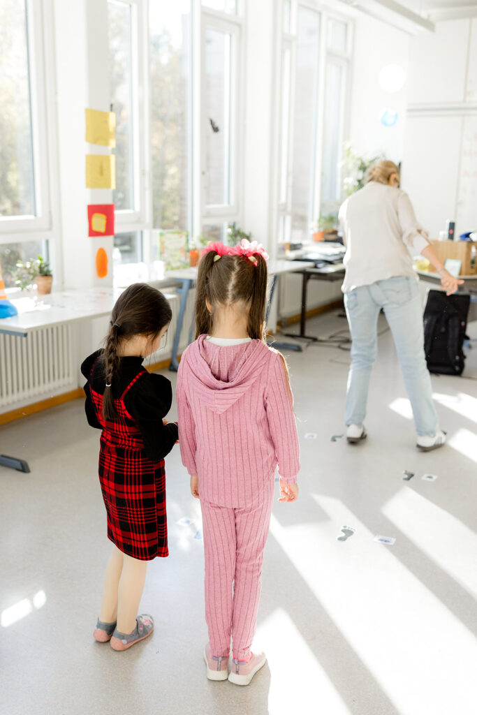 Zwei Kinder gehen gemeinsam durch das Klassenzimmer