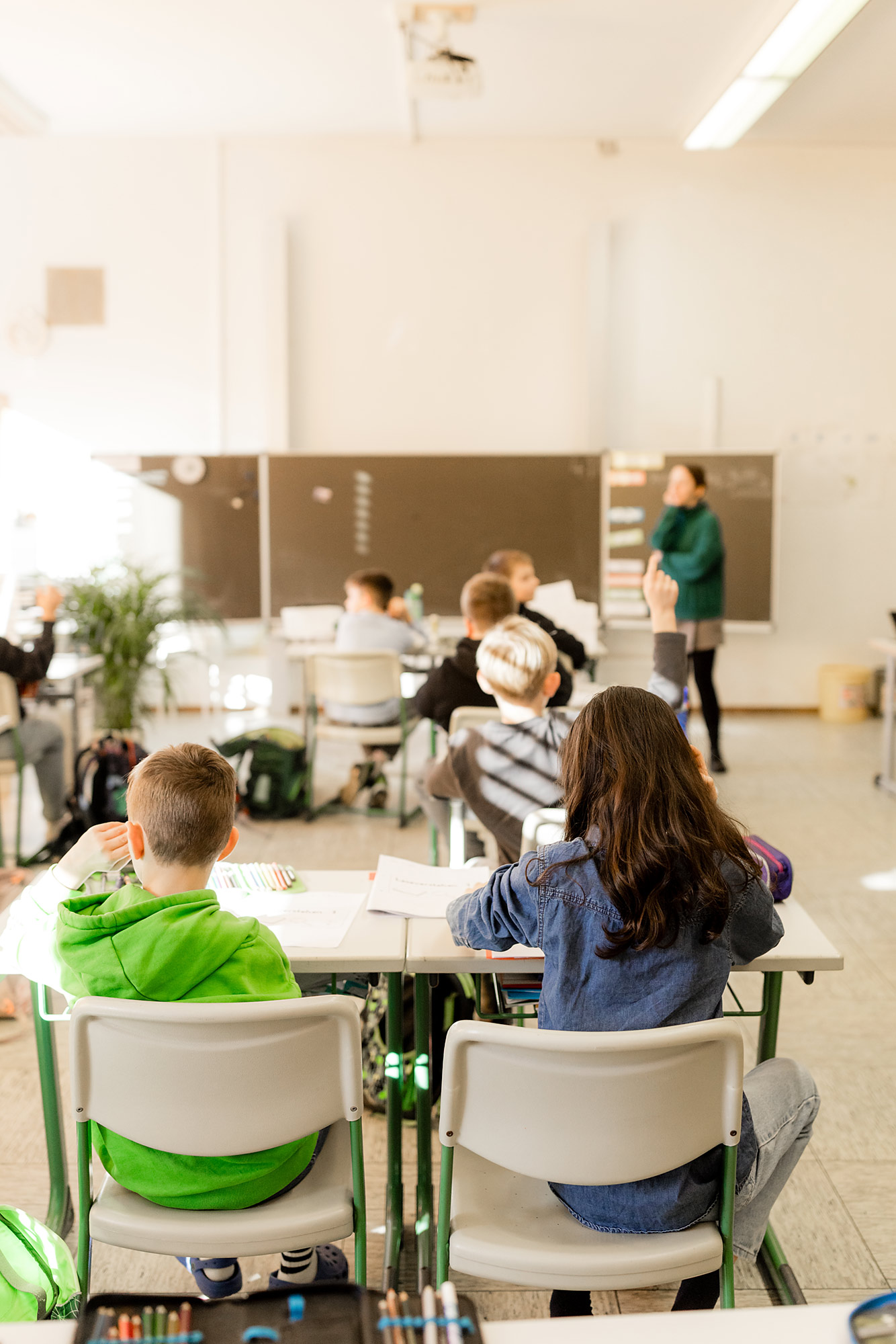 Kinder sitzen im Klassenzimmer und arbeiten mit der Lehrerin