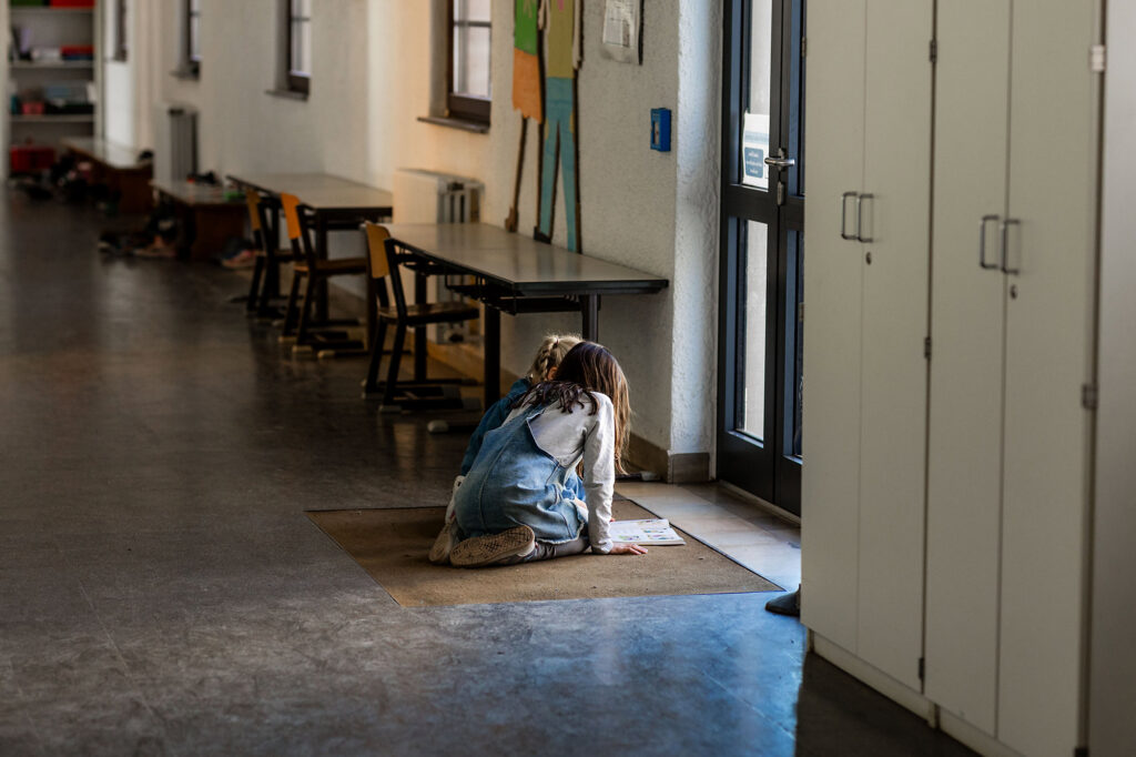 Kinder sitzen im Flur des Schulgebäudes und lernen