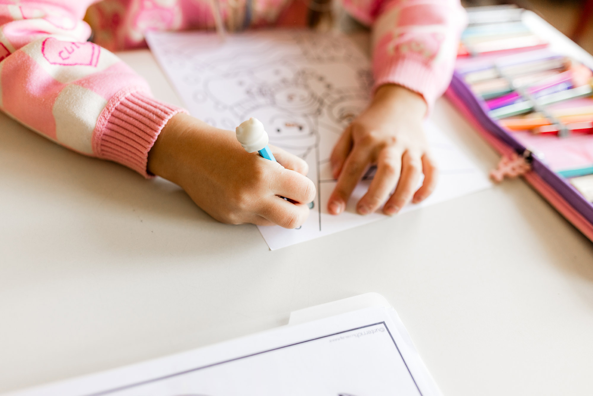 Kind schreibt mit einem Stift auf ein Blatt Papier